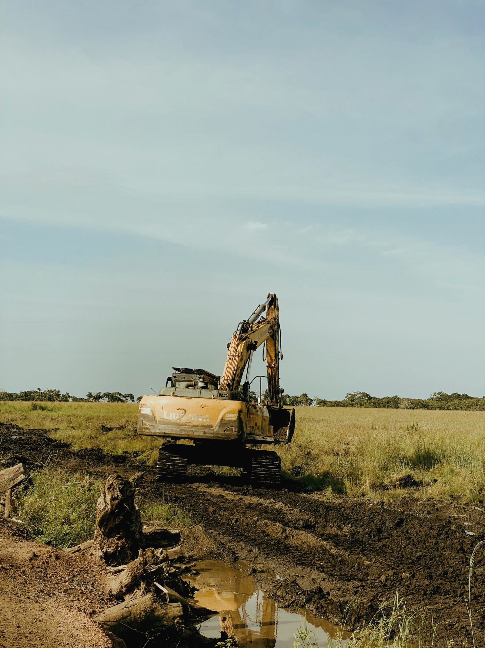 Excavator digging at the edge of an open field
